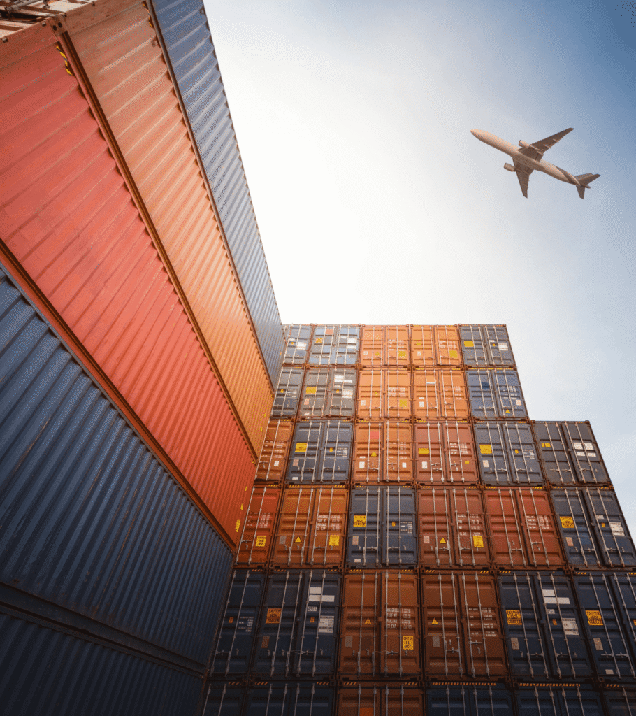 Shipping containers stacked with an airplane flying above them